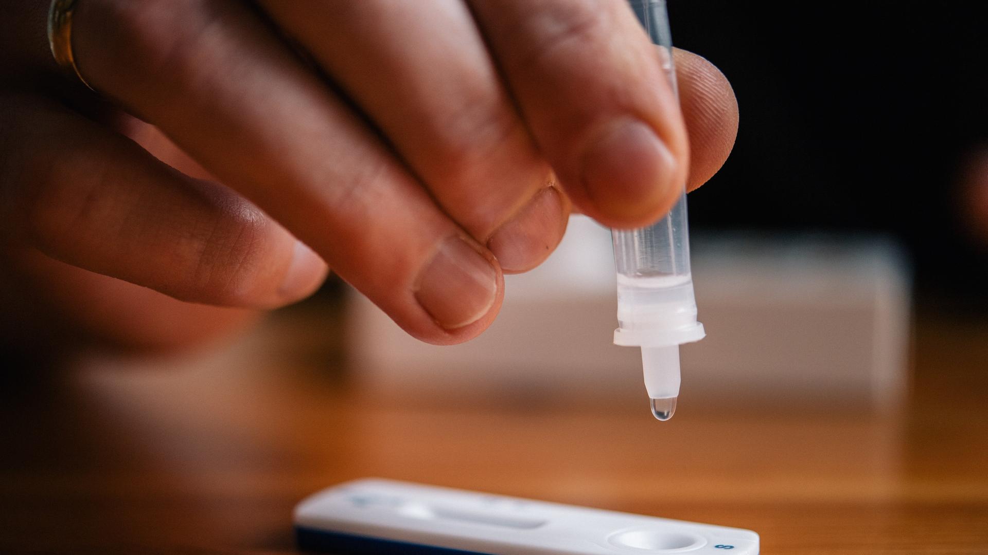 Eine Person träufelt die Probelösung eines Corona-Schnelltests auf die Testkassette Eine Person träufelt die Probelösung eines Corona-Schnelltests auf die Testkassette