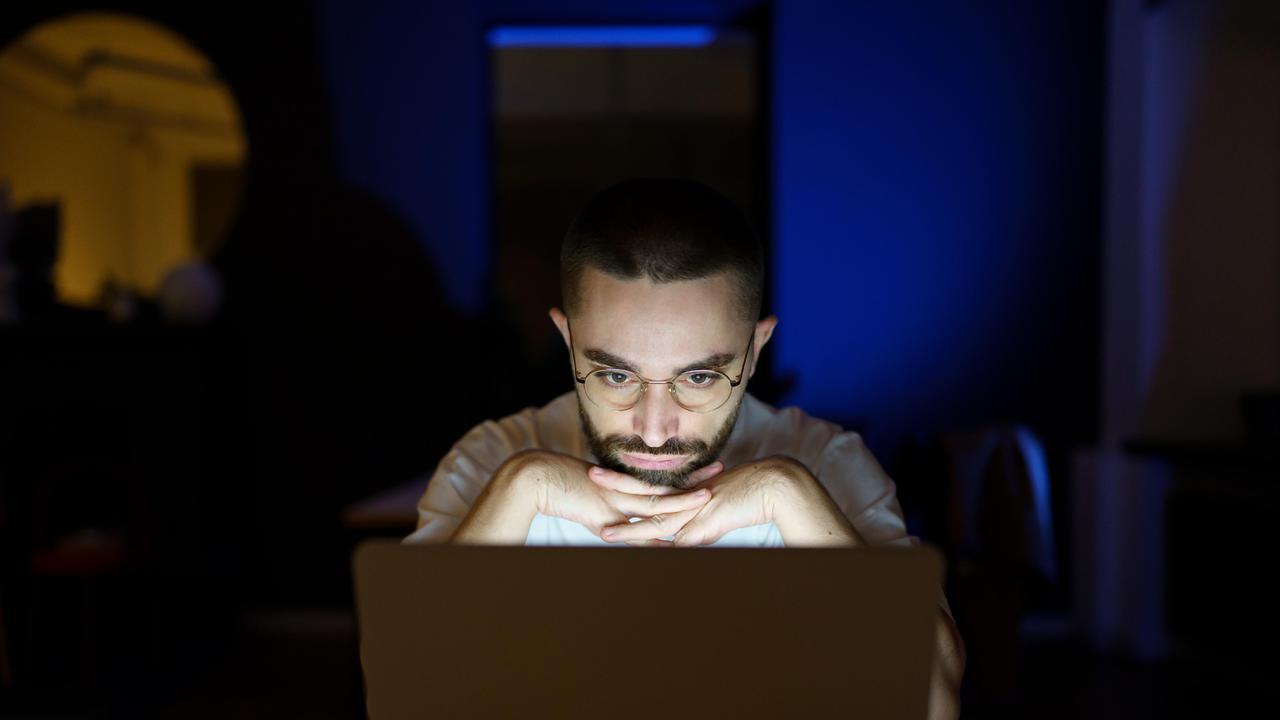 Mann schaut nachdenklich auf Laptop
