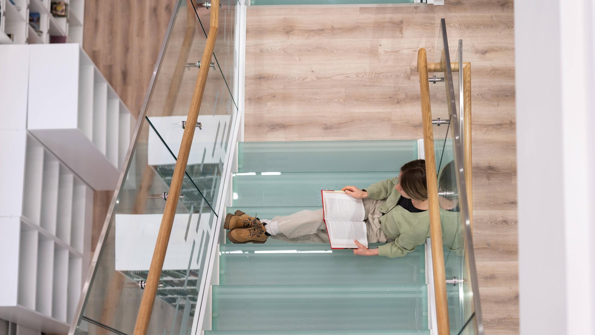 Fleißige Studentin bereitet sich auf Kursarbeit vor, indem sie Bücher liest, um Informationen zu finden.