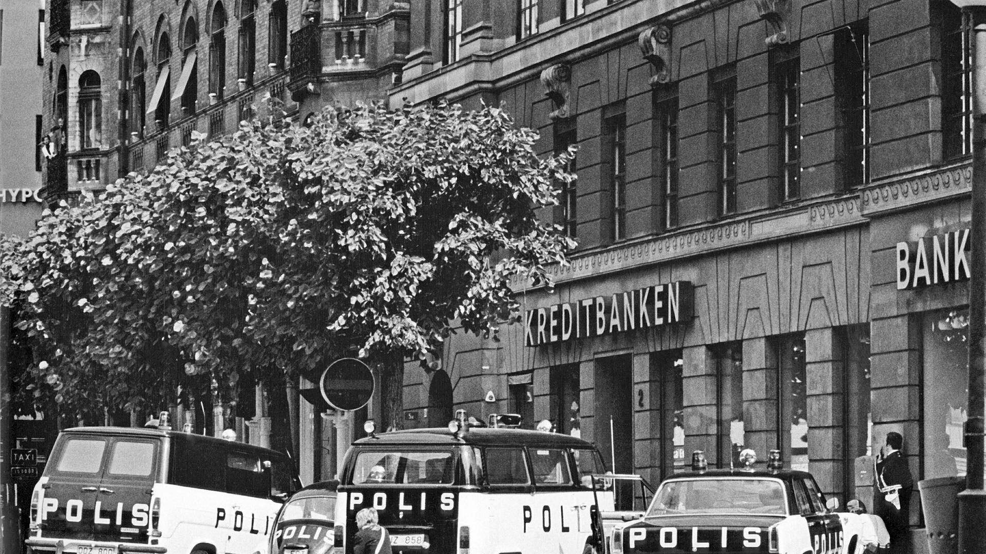 Archivfoto in schwarz-weiß: Polizeiautos stehen vor einem Gebäude. Kreditbanken und Bank steht an dem Haus. Es ist die Geiselnahme in Stockholm im August 1973. Archivfoto in schwarz-weiß: Polizeiautos stehen vor einem Gebäude. Kreditbanken und Bank steht an dem Haus. Es ist die Geiselnahme in Stockholm im August 1973.