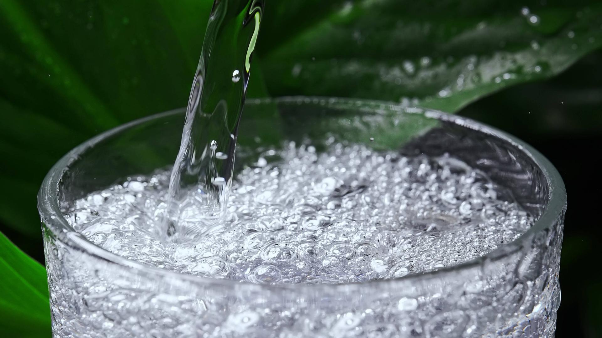 Mineralwasser mit Kohlensäure wird in ein Glas gegossen.