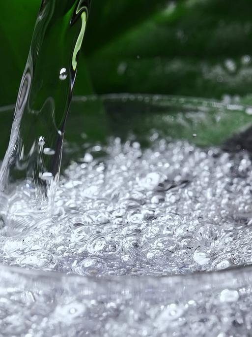 Mineralwasser mit Kohlensäure wird in ein Glas gegossen.