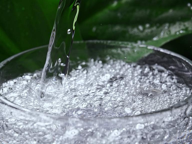 Mineralwasser mit Kohlensäure wird in ein Glas gegossen.
