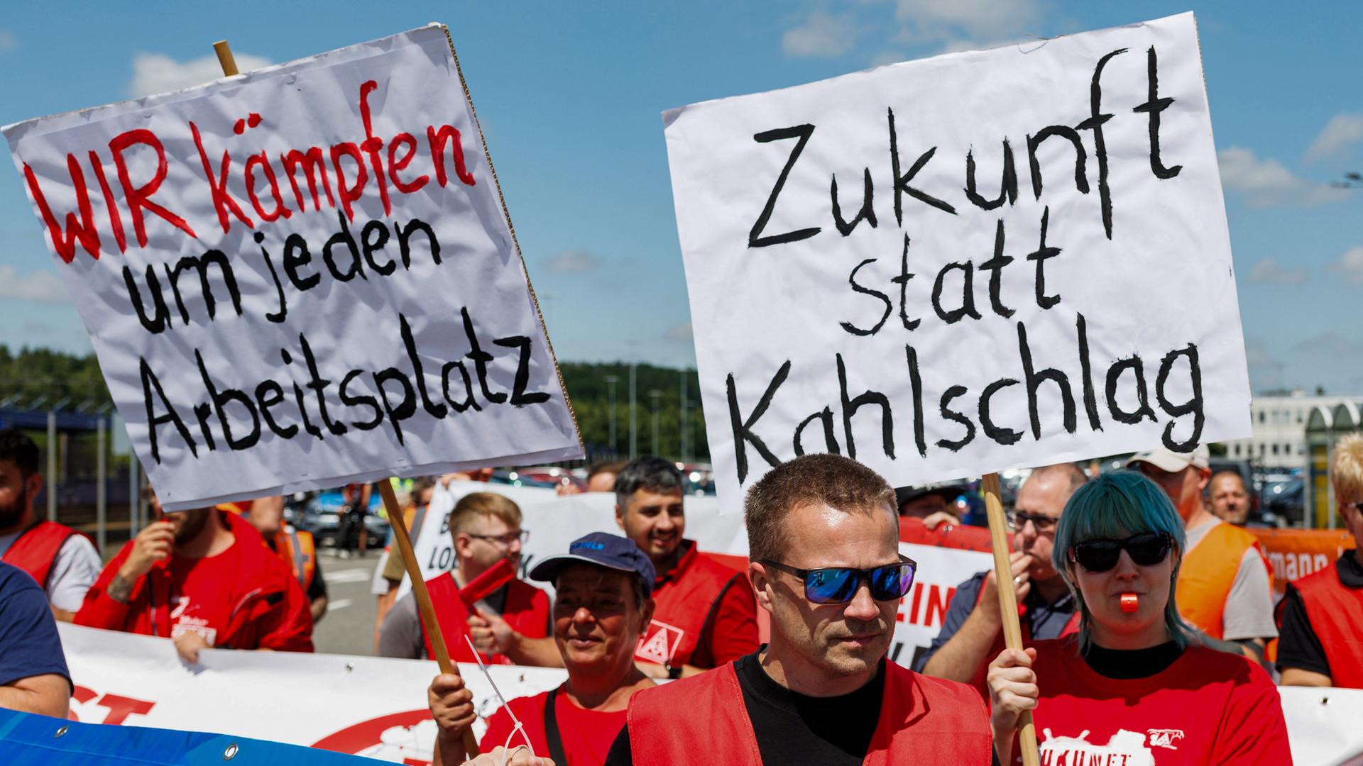 Mitarbeiter von Volkswagen (VW) halten bei einer von der IG Metall organisierten Kundgebung Schilder mit den Aufschriften „Wir kämpfen um jeden Arbeitsplatz“ (links) und „Zukunft statt Kahlschlag“ in die Höhe (9.07.2026, Zwickau) Mitarbeiter von Volkswagen (VW) halten bei einer von der IG Metall organisierten Kundgebung Schilder mit den Aufschriften „Wir kämpfen um jeden Arbeitsplatz“ (links) und „Zukunft statt Kahlschlag“ in die Höhe (9.07.2026, Zwickau)