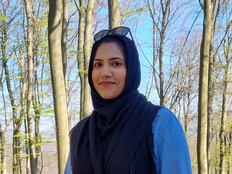 Humaira Waseem blickt in die Kamera, sie steht in einem Wald.