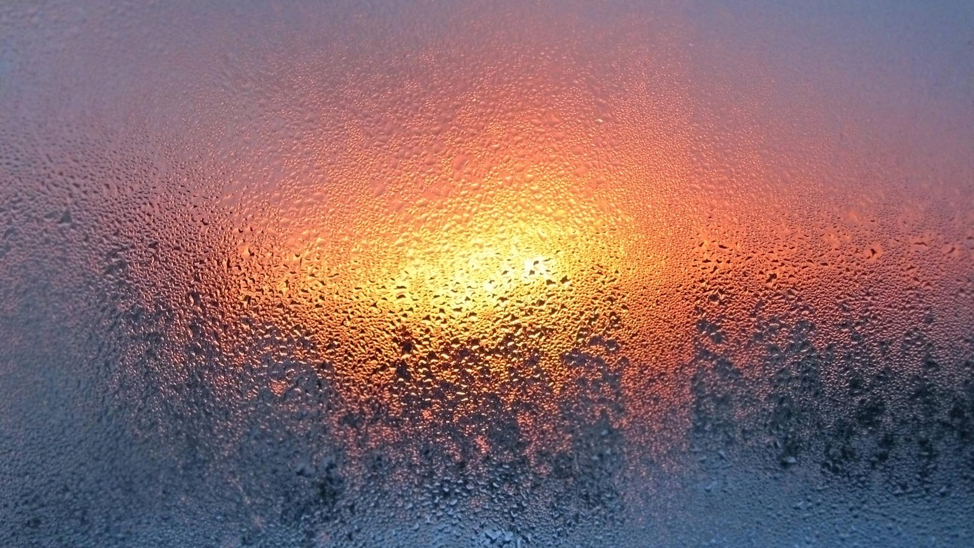 Natürliche Wassertropfen und Sonnenlicht auf Fensterglas.