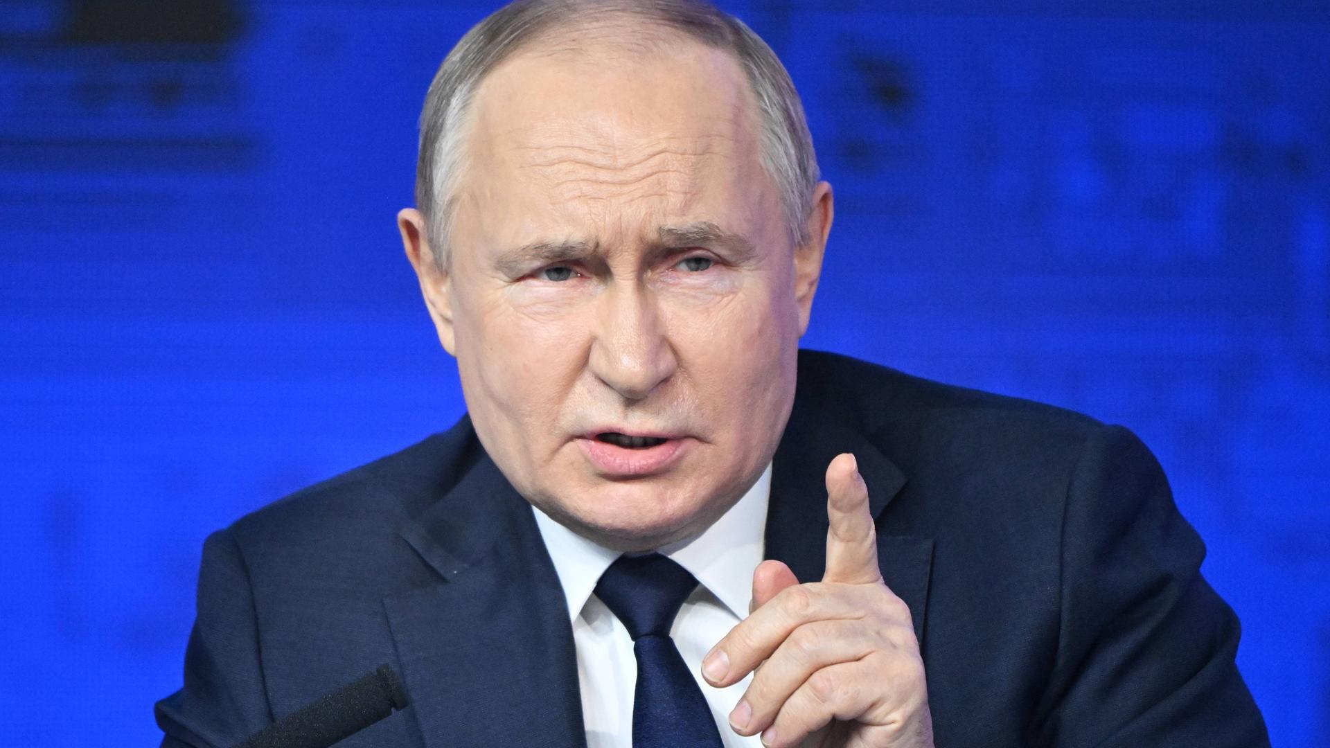 Der russische Präsident Wladimir Putin spricht hebt die linke Hand ein wenig hoch.