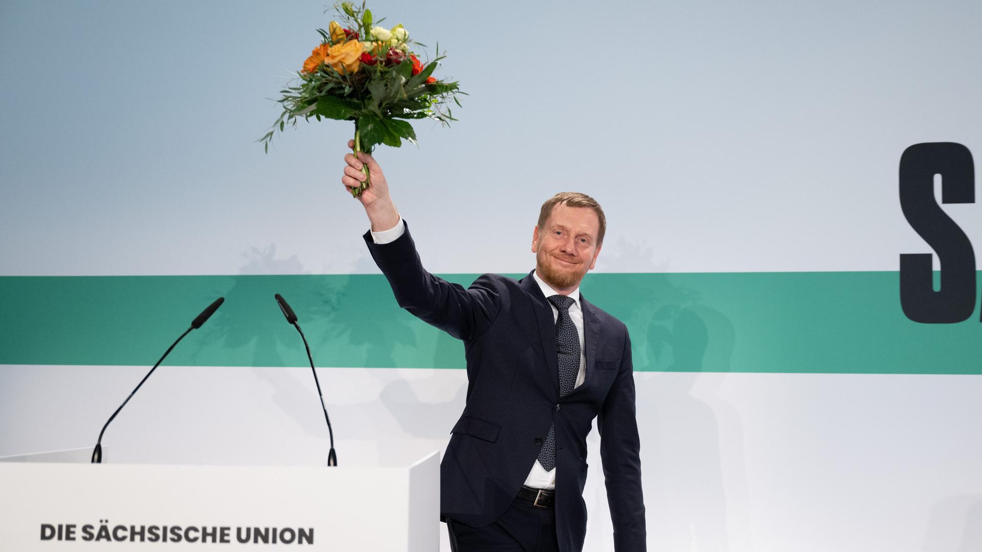 Michael Kretschmer (CDU), Ministerpräsident von Sachsen, hält nach seiner Wahl auf der Landesvertreterversammlung der CDU Sachsen einen Blumenstrauß.