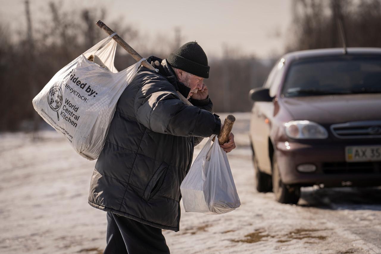 Ukraine, Netschwolodiwka: Ein Mann trägt Säcke mit Gütern, die er als humanitäre Hilfe im Dorf Netschwolodiwka erhalten hat. 