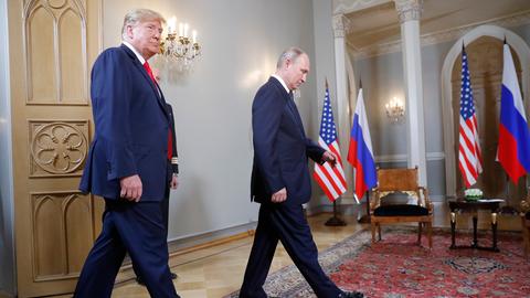 Us-Präsident Trump und Russlands Prösident Putin laufen durch einen Raum, im Hintergrund sieht man die Flaggen von Russland und den USA.