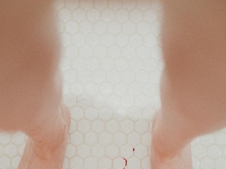 Zwei Füße in Dusche mit Blutfleck