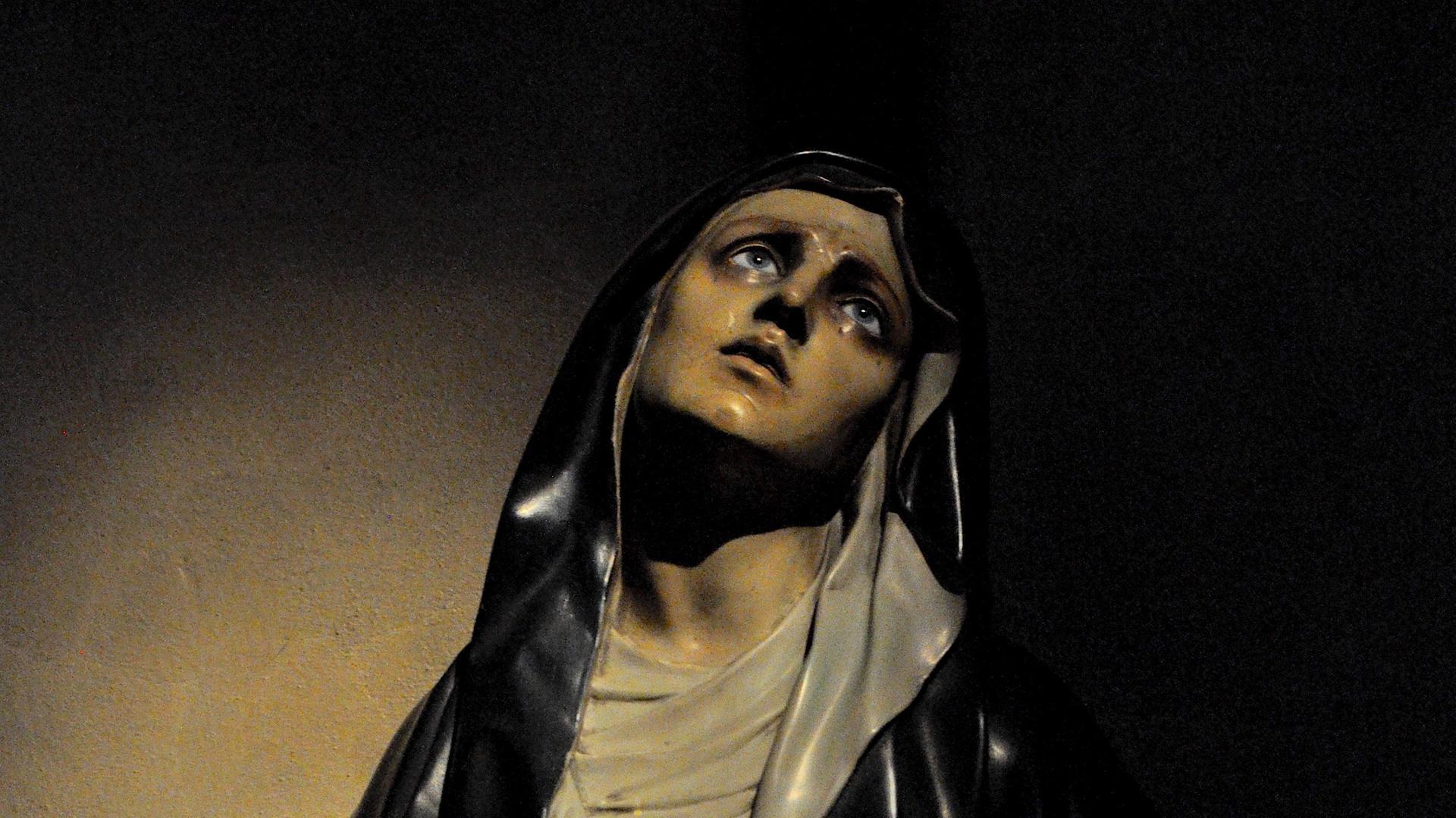 Die Figur einer Frau blickt voll Trauer nach oben. Es ist die Mutter Jesu. Es ist eine Darstellung aus einer italienischen Kirche.