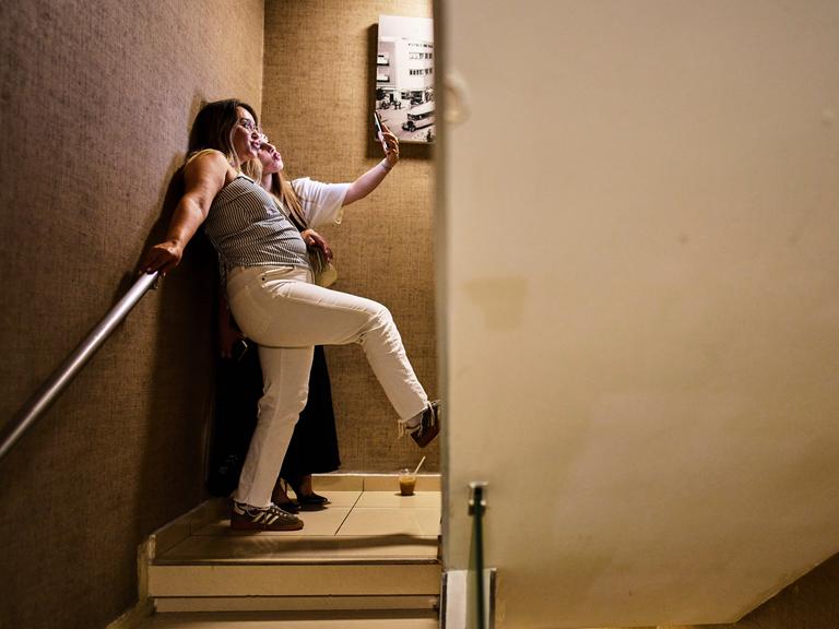 Zwei Frauen stehen in einem Hoteltreppenhaus zum Schutzkeller in Tel Aviv und machen mti einem Handy ein Selfie.