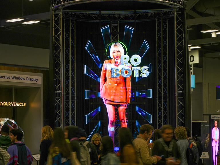 Auf einem Display auf dem South-by-Southwest-Festival in Austin ist die graphische Darstellung einer Frau zu sehen, vor ihr steht das Wort "Robots" geschrieben. 