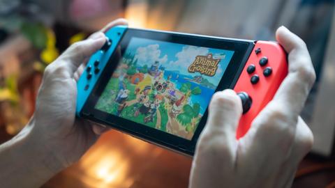 Hände halten eine Nintendo Switch und spielen darauf das Spiel "Animal Crossing"