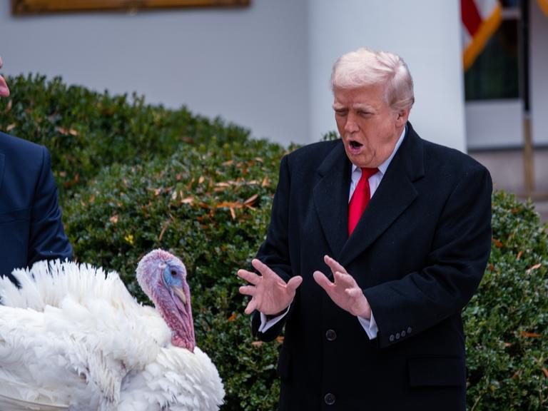US-Präsident Trump steht im Garten vor einem weißen Truthahn.