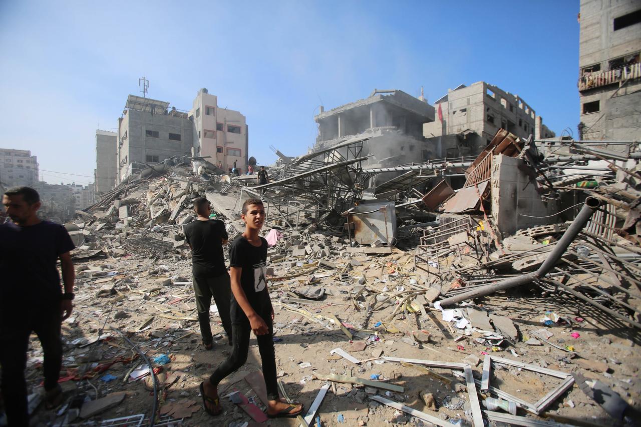 Ein junger Mann geht an den Trümmern des Al-Shati Flüchtlingscamps in Gaza-Stadt vorbei, ein anderer steht davor.