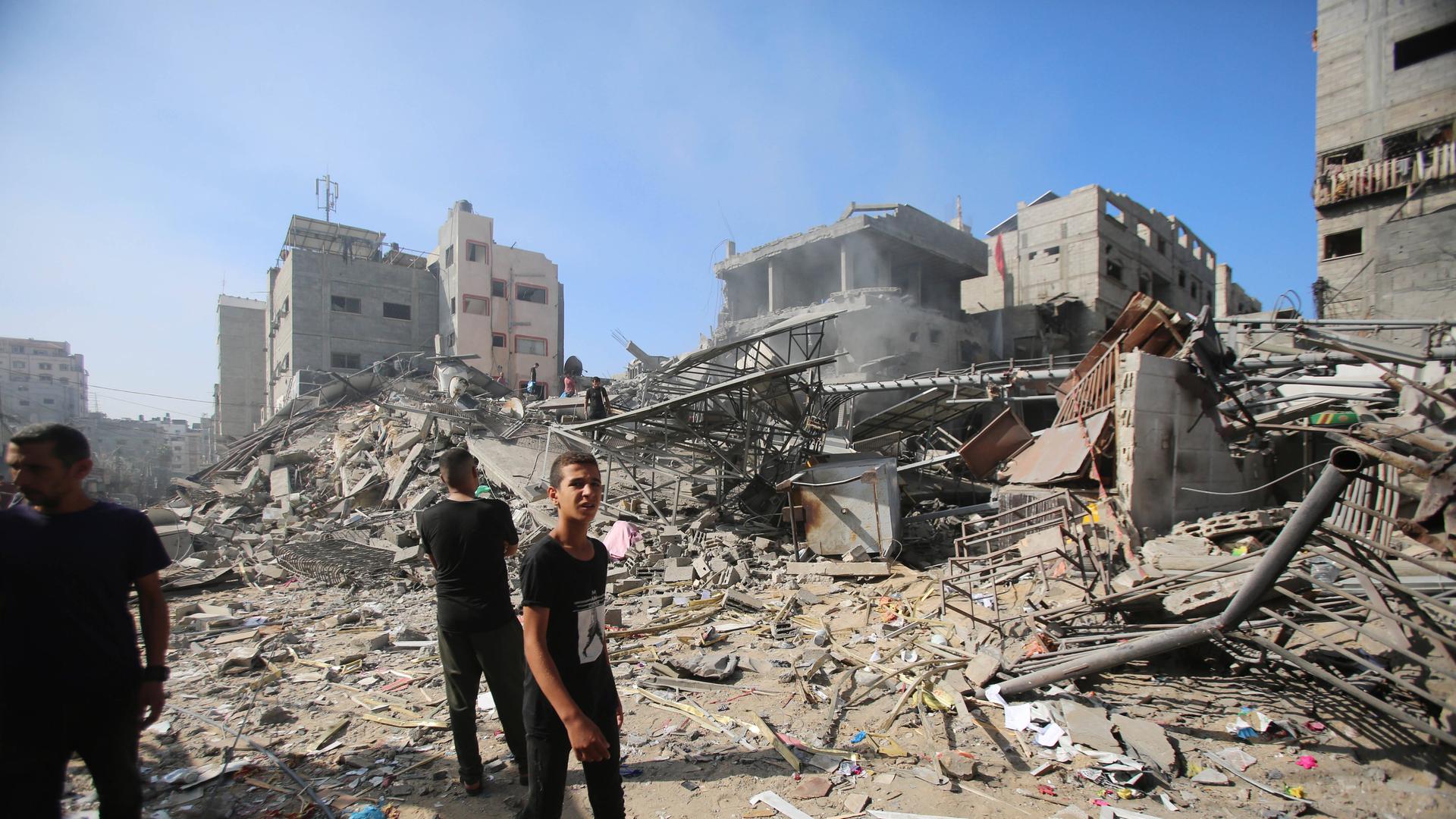 Ein junger Mann geht an den Trümmern des Al-Shati Flüchtlingscamps in Gaza-Stadt vorbei, ein anderer steht davor.