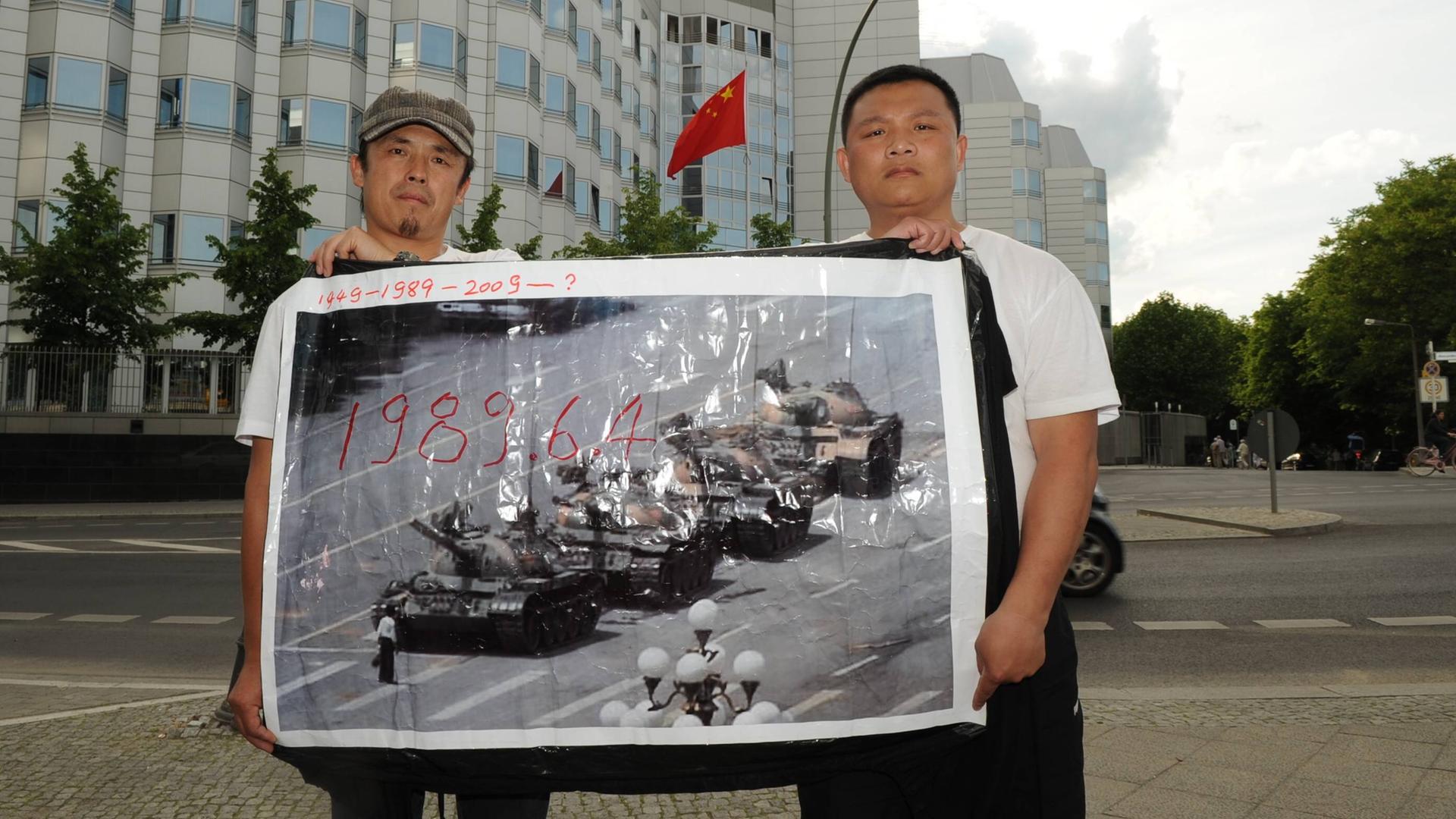 Zwei Demonstranten erinnern mit einem historischen Foto an die Niederschlagung der Protestbewegung auf dem Tiananmenplatz 1989  vor der Chinesischen Botschaft in Berlin. 