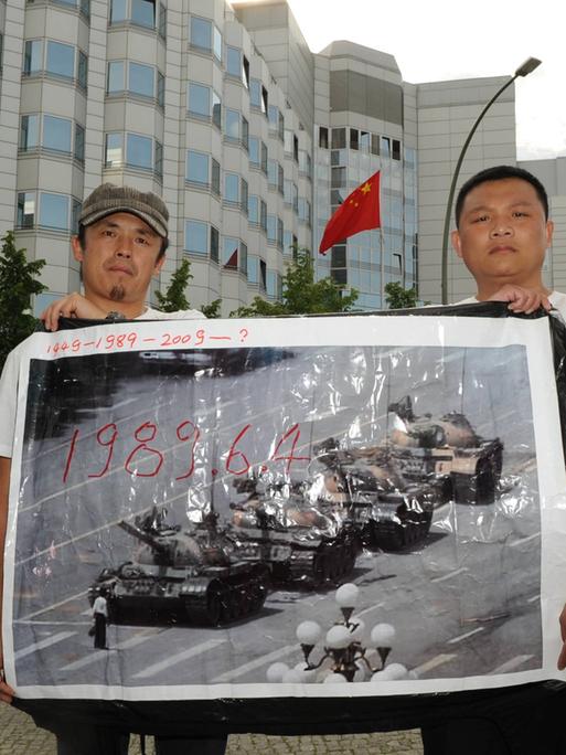 Zwei Demonstranten erinnern mit einem historischen Foto an die Niederschlagung der Protestbewegung auf dem Tiananmenplatz 1989  vor der Chinesischen Botschaft in Berlin. 