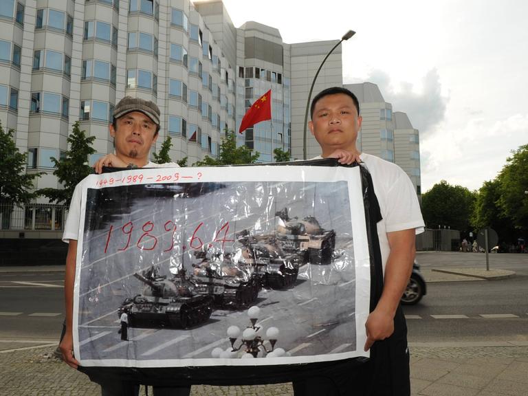 Zwei Demonstranten erinnern mit einem historischen Foto an die Niederschlagung der Protestbewegung auf dem Tiananmenplatz 1989  vor der Chinesischen Botschaft in Berlin. 