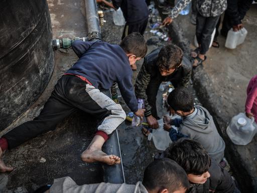 Palästinensische Kinder füllen Flaschen mit Wasser, das von Wohltätigkeitsorganisationen verteilt wurde, da der Zugang zu sauberem Wasser aufgrund der anhaltenden israelischen Blockade in Rafah immer schwieriger wird.