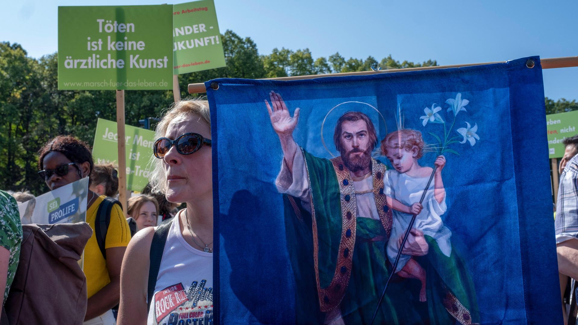 Mehrere Hundert Abtreibungsgegner demonstrieren am Samstag (16.09.2023) im Zentrum Berlins für einen unbedingten Lebensschutz. Eine Frau hält ein Transparent mit Jesus und einem Kind darauf.