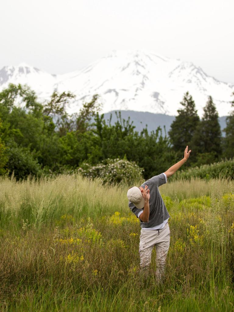 Teenager tanzt in ländlicher Umgebung vor Bergpanorama.