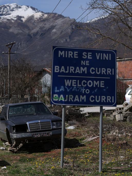 Das Ortseingangsschild einer Kleinstadt trägt die Aufschrift: "Willkommen in Bajram Curri" auf Albanisch und Englisch.
