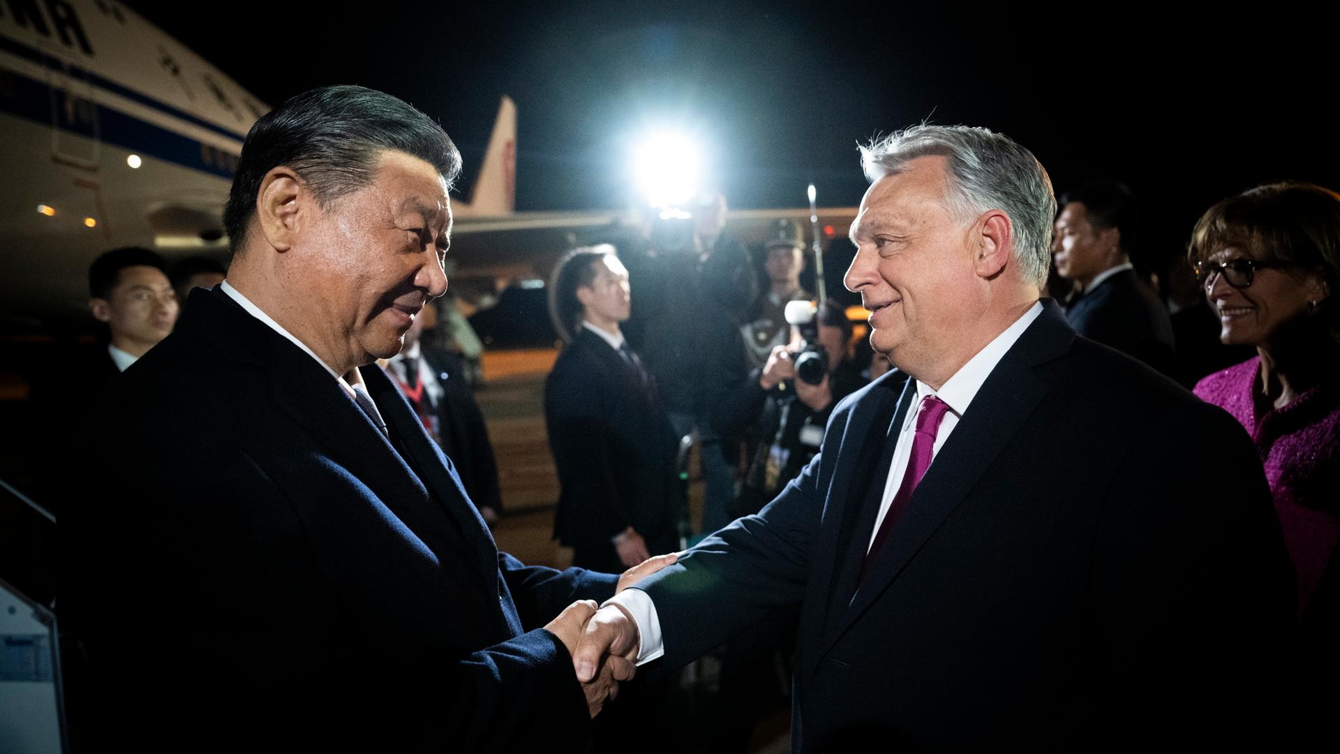 Der chinesische Präsident Xi wird in Budapest vom ungarischen Ministerpräsidenten Orban begrüßt. Beide lächeln freundlich und schütteln einander die Hand. Aufnahme vom 09.05.2024. 