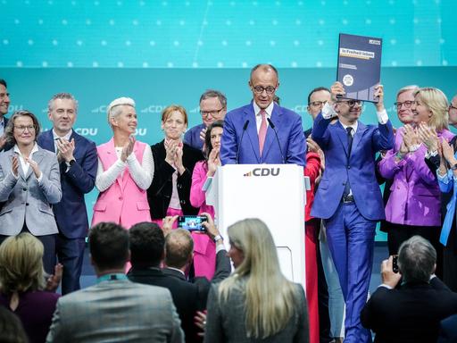 Friedrich Merz steht gemeinsam mit Deligierten auf der Bühne des CDU-Parteitages.