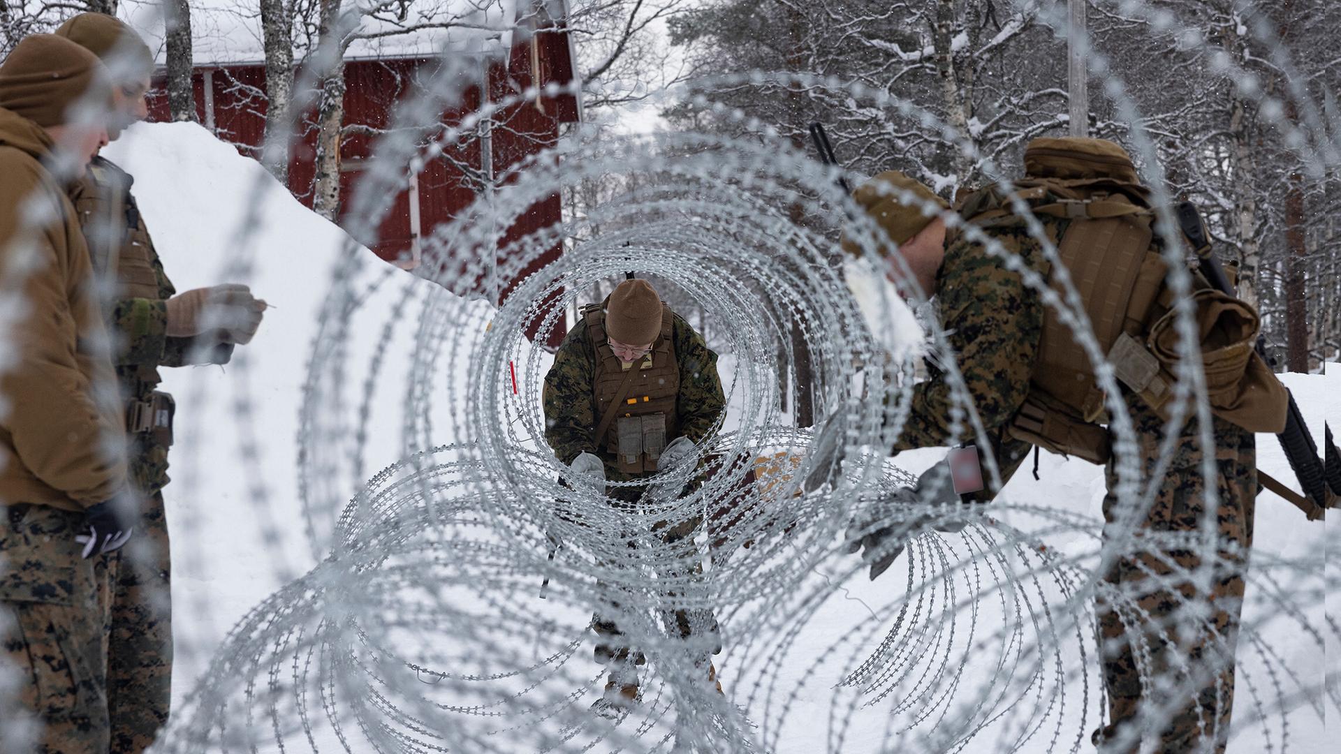Soldaten bringen NATO-Stacheldraht in schneebedeckter Umgebung an. Soldaten bringen NATO-Stacheldraht in schneebedeckter Umgebung an.