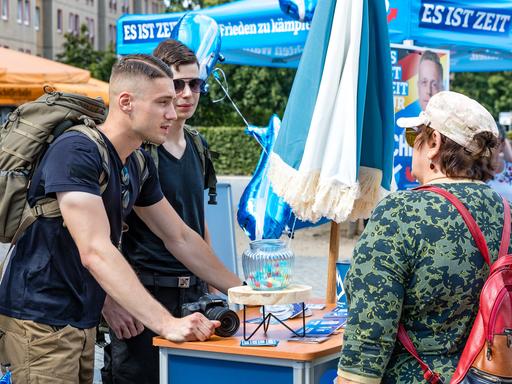 Mitglieder der Jungen Alternative, der Jugendorganisation der AfD, sprechen auf einer Wahlkampfveranstaltung der AfD Brandenburg in Cottbus mit einer Besucherin der Veranstaltung.