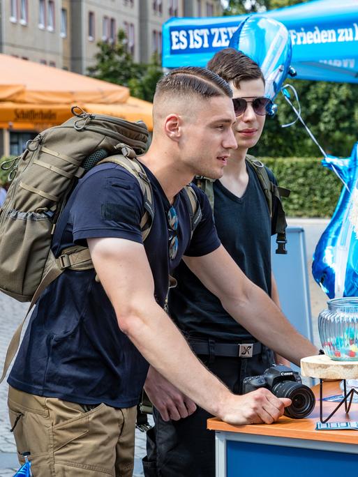 Mitglieder der Jungen Alternative, der Jugendorganisation der AfD, sprechen auf einer Wahlkampfveranstaltung der AfD Brandenburg in Cottbus mit einer Besucherin der Veranstaltung.