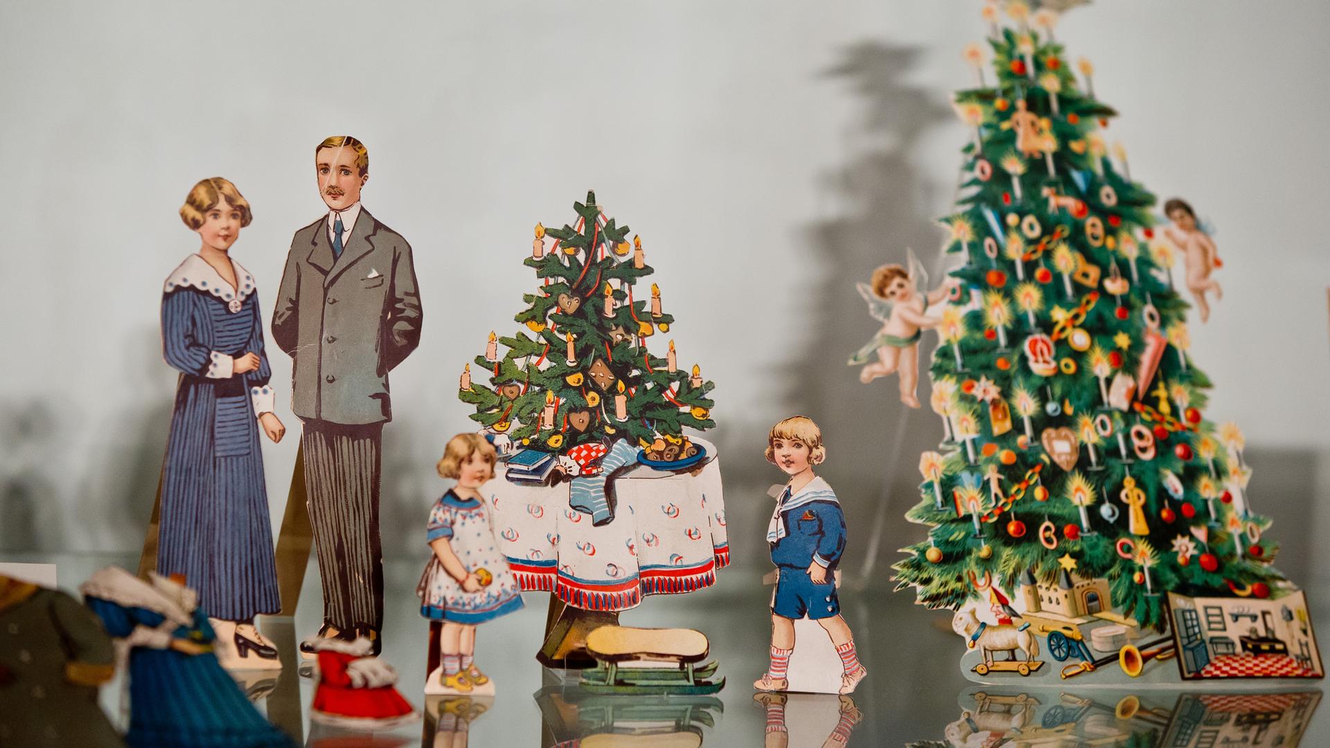 Ankleidepuppen mit Kleidungsstücken stehen an einem Spielzeugweihnachtsbaum mit Geschenken. Ankleidepuppen mit Kleidungsstücken stehen an einem Spielzeugweihnachtsbaum mit Geschenken.