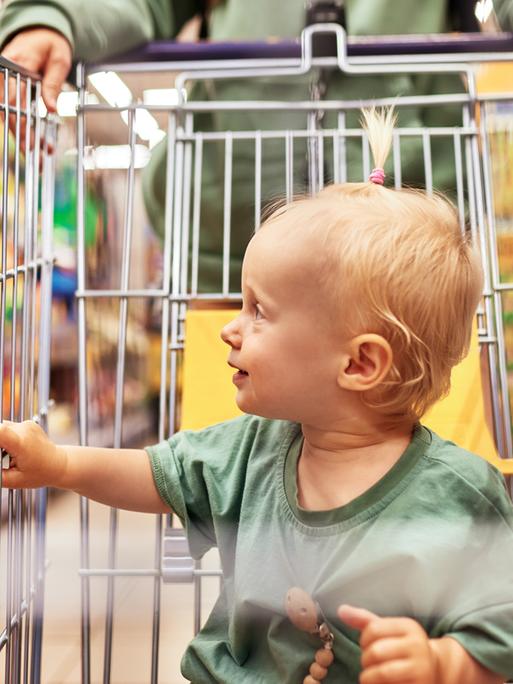 Ein Baby sitzt im Einkaufswagen.