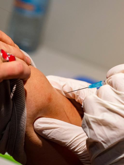 Eine Frau bekommt die eine mRNA-Coronaimpfung in den Oberarm.