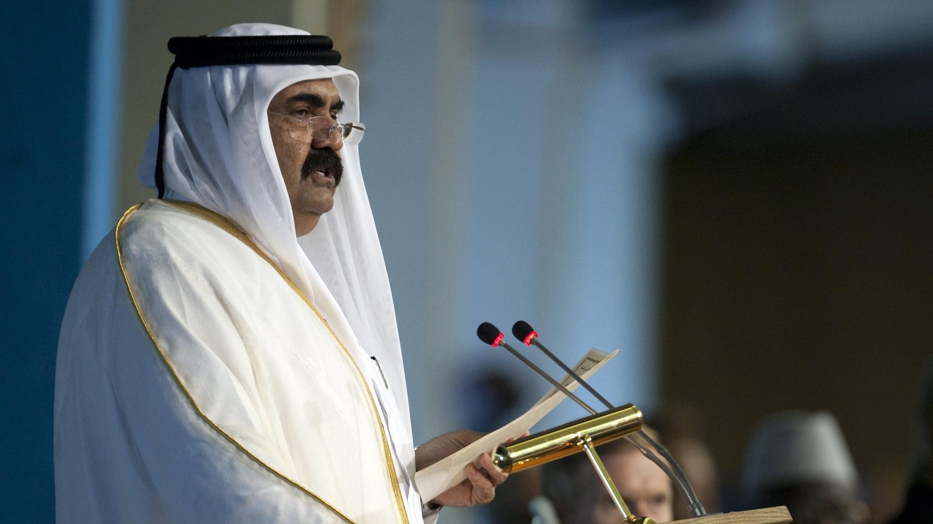 Scheich Hamad bin Chalifa Al Thani steht an einem Pult und hält eine Ansprache.  
