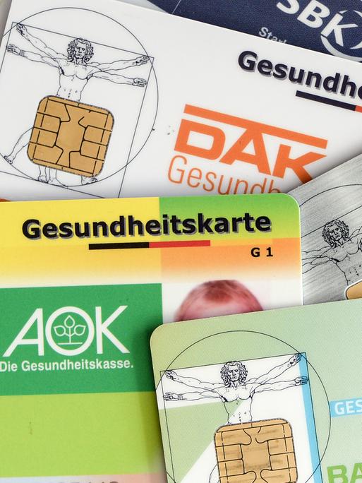 Mehrere Gesundheitskarten verschiedener Krankenkassen liegen auf einem Tisch. Mehrere Gesundheitskarten verschiedener Krankenkassen liegen auf einem Tisch.