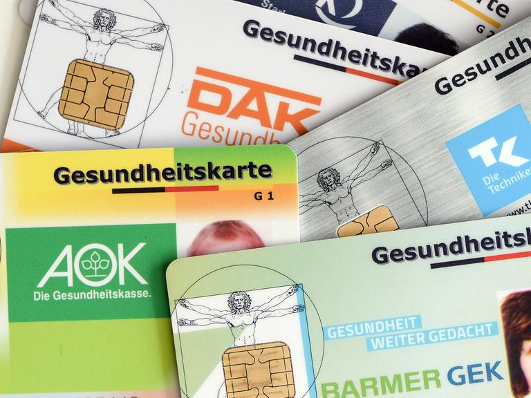 Mehrere Gesundheitskarten verschiedener Krankenkassen liegen auf einem Tisch. Mehrere Gesundheitskarten verschiedener Krankenkassen liegen auf einem Tisch.
