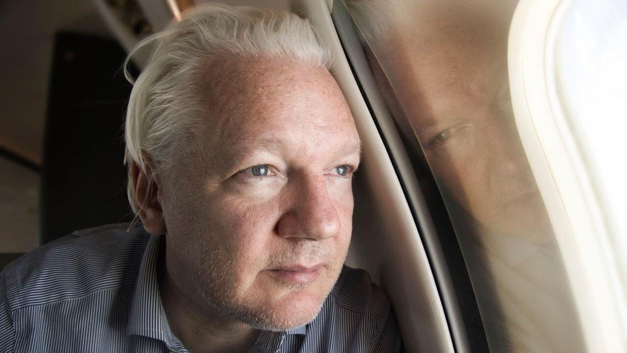 Julian Assange lehnt seinen Kopf an ein Flugzeugfenster und schaut hinaus. Julian Assange lehnt seinen Kopf an ein Flugzeugfenster und schaut hinaus.