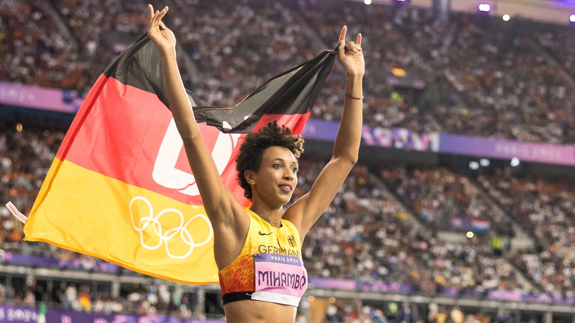 Die deutsche Weitspringerin Malaika Mihambo hält die deutsche Fahne hoch und feirte bei den Olympischen Spielen in Paris den Gewinn der Silbermedaille.