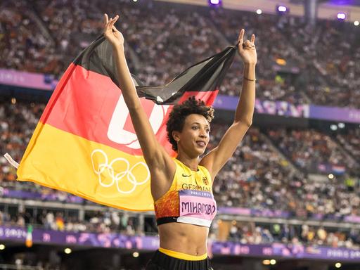 Die deutsche Weitspringerin Malaika Mihambo hält die deutsche Fahne hoch und feirte bei den Olympischen Spielen in Paris den Gewinn der Silbermedaille.