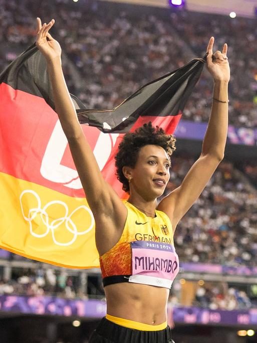 Die deutsche Weitspringerin Malaika Mihambo hält die deutsche Fahne hoch und feirte bei den Olympischen Spielen in Paris den Gewinn der Silbermedaille.