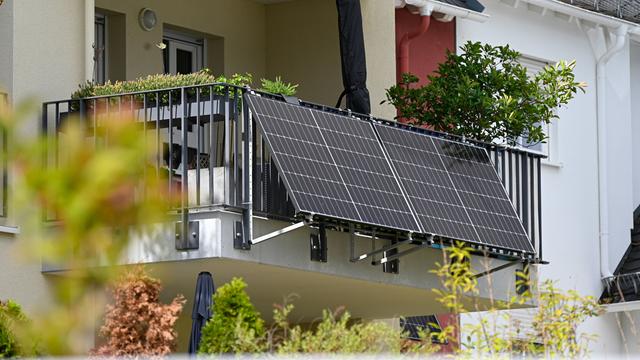 Am Balkongeländer eines Mehrfamilienhauses hängen Solarmodule.