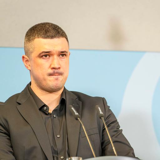 Mychajlo Fedorow steht an einem Rednerpult vor zwei Mikrofonen.