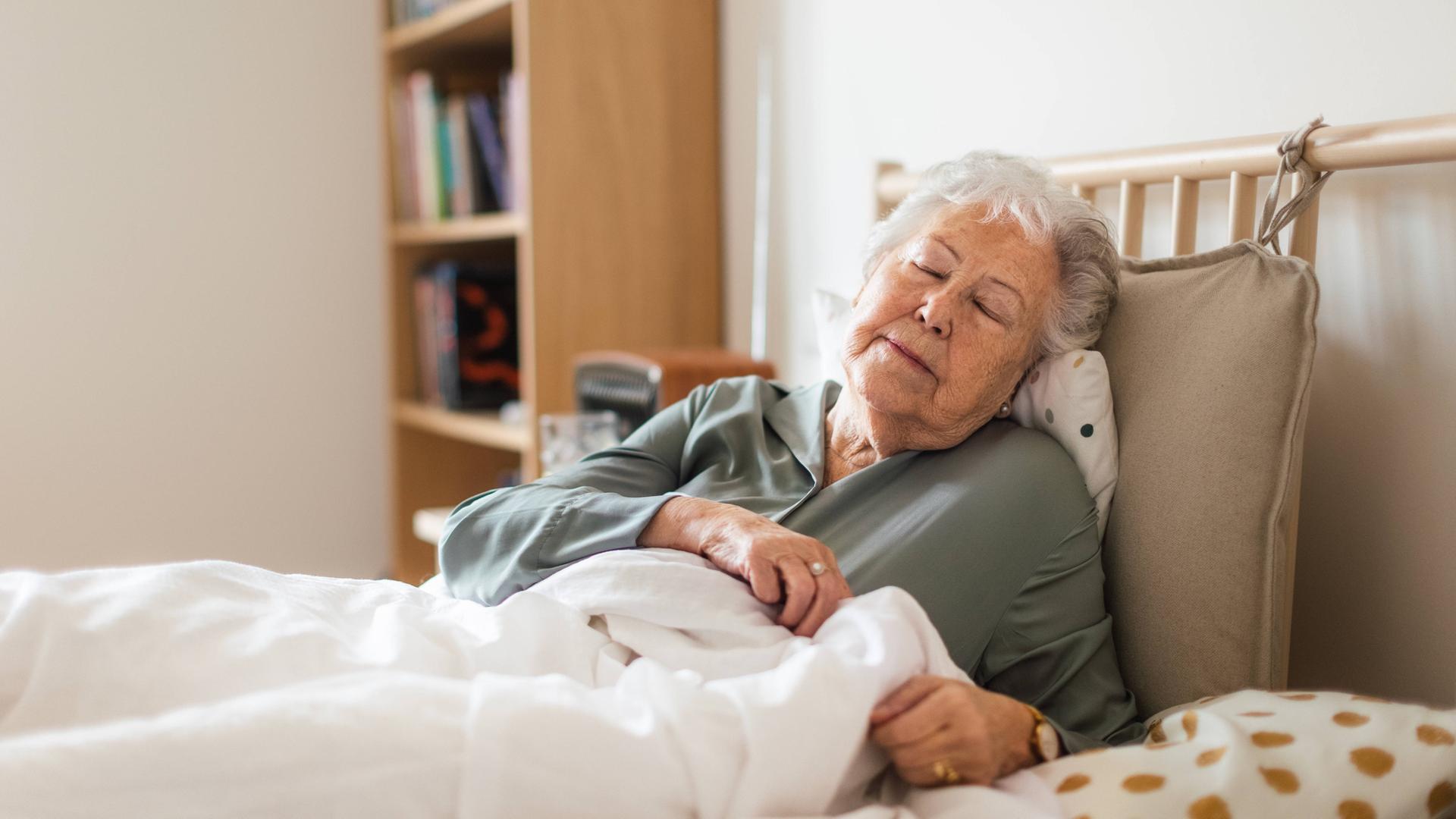 Eine ältere Frau liegt im Bett. Sie hat die Augen geschlossen. Eine ältere Frau liegt im Bett. Sie hat die Augen geschlossen.