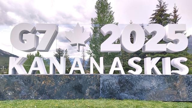 In einer Landschaft mit Wald stehen weiße Buchstaben. Die bilden das Logo für den G7-Gipfel in Kanada. 