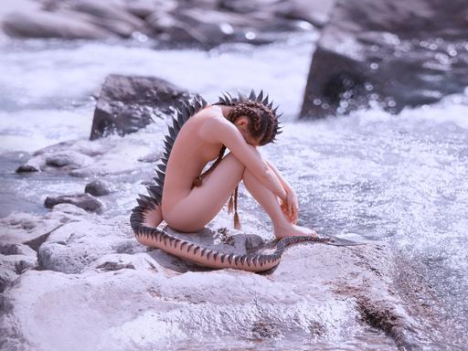 Ein Meerjungfrau-Alien sitzt auf einem Stein im Fluss und ist in sich gekauert.