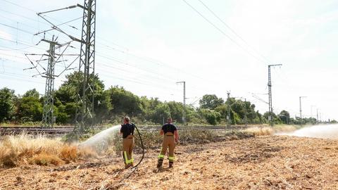 Einsatzkräfte der Feuerwehr löschen einen Böschungsbrand an der wichtigen Bahnstrecke zwischen Düsseldorf und Köln.